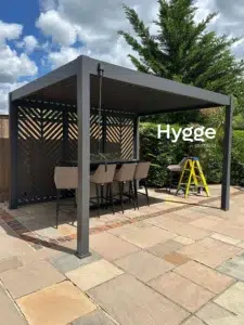Freestanding dark grey aluminium pergola with an outdoor dining area, offering weather protection and style.